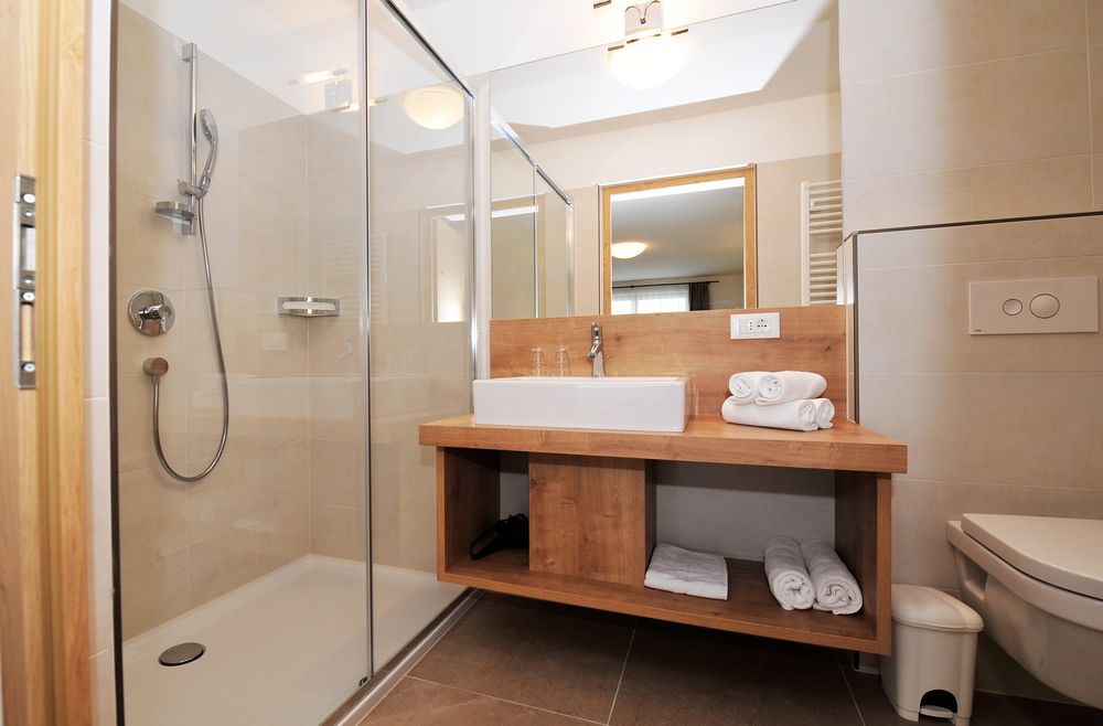 Modernes Bad mit Dusche, Waschbecken und Holzablage mit Handtüchern