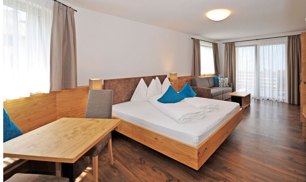 Helles Hotelzimmer mit Doppelbett, Sitzbereich und Balkon.