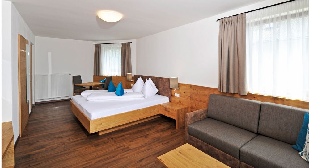 Modern eingerichtetes Hotelzimmer mit Bett, Sofa und Tisch