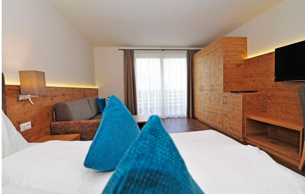 Modernes Hotelzimmer mit Holzvertäfelung, Bett, Sofa und Balkon