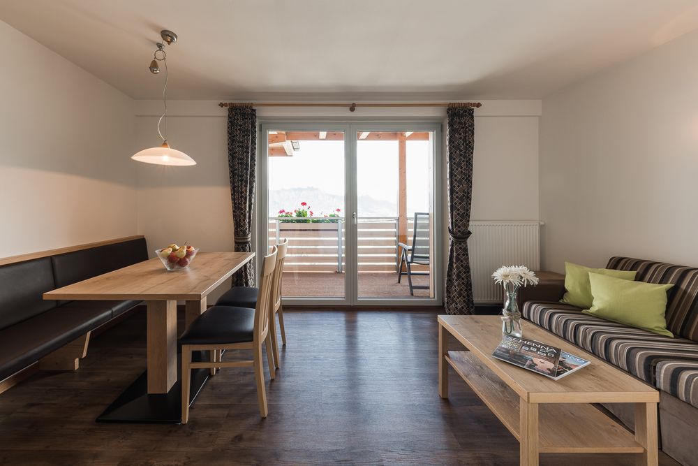 Hell eingerichtetes Wohnzimmer mit Essbereich, Sofa und Balkon mit Ausblick