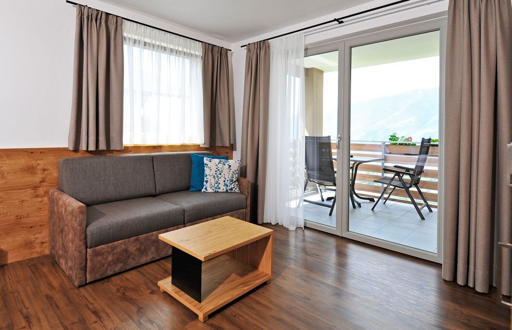 Modernes Wohnzimmer mit Sofa, kleinem Holztisch und Balkon mit Bergblick