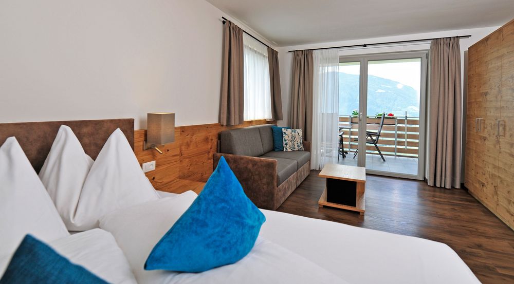 Modernes Hotelzimmer mit Bett, Sofa, Balkon und Bergblick